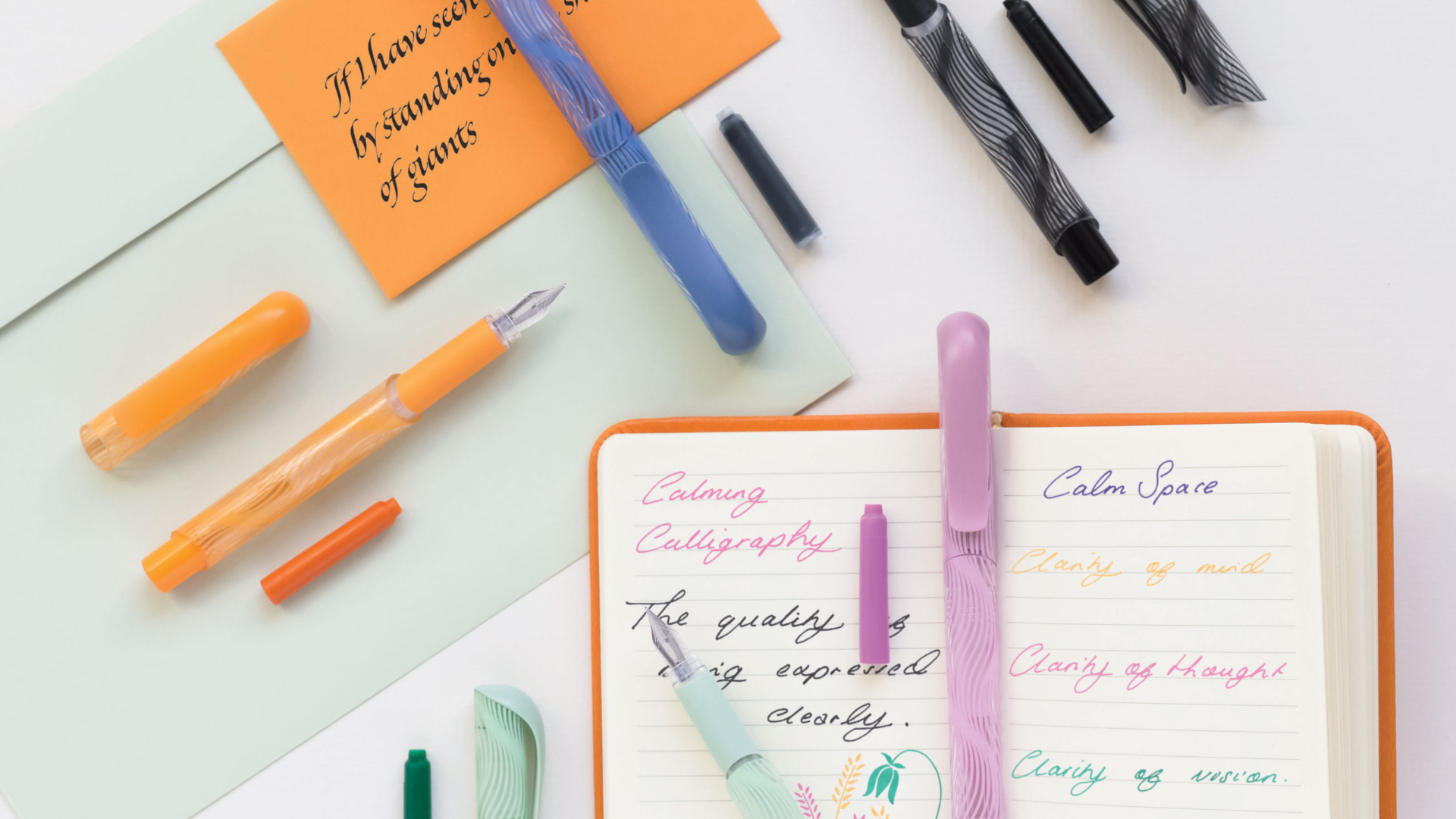 Five Clarity colourful fountain pens on an aesthetic desk layout with notebook and envelopes.