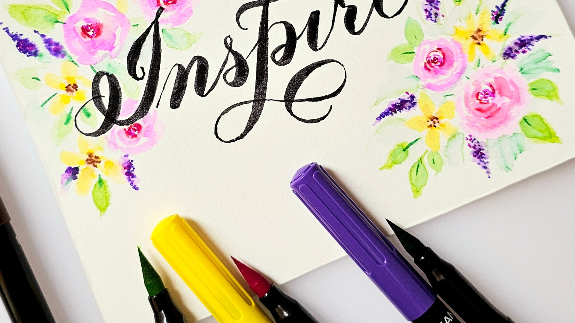 An image of brush pen calligraphy that says "Inspire" with floral decorations in the corners of the page.